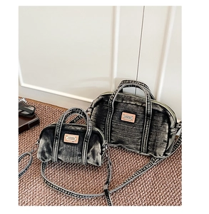 Détail de sacs polochons en denim délavé avec logo en cuir et bandoulières amovibles