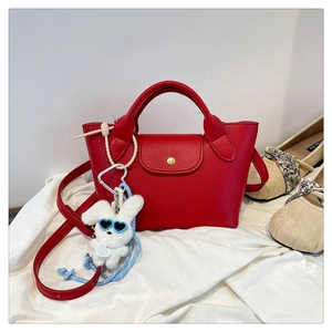 Detailed shot of red litchi grain leather tote with gold buckle and plush bunny charm