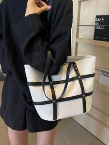 Minimalist black and white tote bag with cross straps and silver rivet details