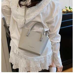 Gray lychee grain leather crossbody bag with silver sphere hardware and debossed text detail