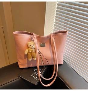 Detail of pink lychee textured leather tote bag with a cute brown bear charm
