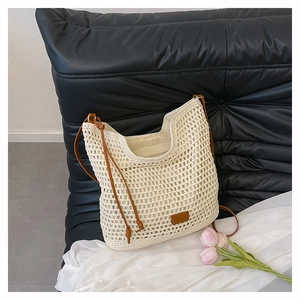 Close-up of woven straw tote bag with brown leather shoulder straps and tulip flower