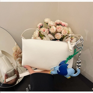 Dettaglio borsa a secchiello bianca in pelle con ciondolo a forma di elefante blu