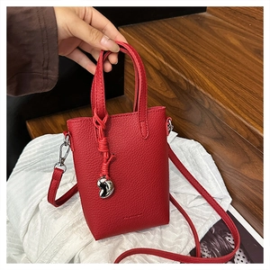 Détail d'un mini sac cabas rouge avec texture litchi, pendentif cœur et logo gaufré