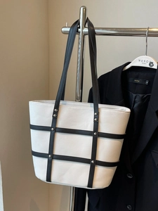 Minimalist canvas tote bag with black leather lattice patterns and silver metal rivets