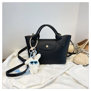 Detail of black pebbled leather mini tote bag with a cute white plush bunny charm
