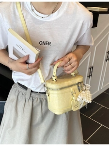 Minimalist yellow leather bucket bag with pleated texture and pearl heart charm