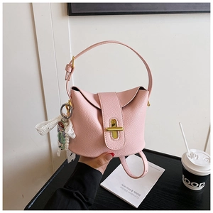 Detailed view of pink litchi grain leather bucket bag with gold clasp and pearl charm