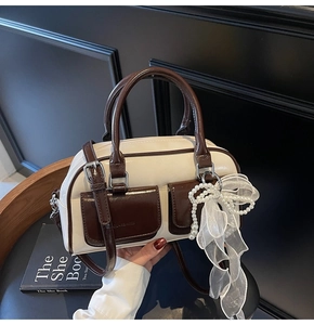 Detail view of contrast color Boston bag featuring pearl chain and mesh bow decoration