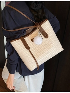 Cream straw tote bag with brown leather straps and pompom charm for summer beach vacation