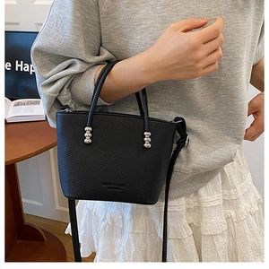 Detail of black lychee texture handbag with elegant silver hardware and leather imprint