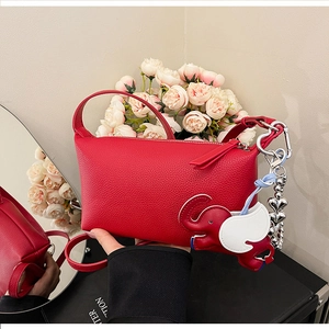 Dettaglio di mini borsa in pelle rossa con ciondolo a elefante e tracolla a catena a cuore