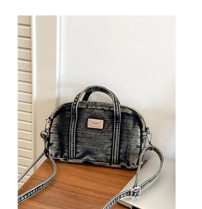 Gros plan du sac Boston en jean gris délavé avec écusson en cuir et détails métalliques