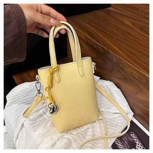 Détail du sac à main en cuir grainé jaune vif avec breloque cœur et logo fashion