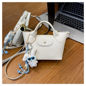 Close-up of mini cream tote bag with lychee grain leather and plush rabbit charm