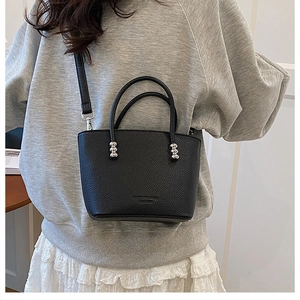 Detail of black lychee texture handbag featuring silver metal bead handle accents