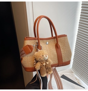 Détail du sac seau en paille avec poignées en cuir et charmant pendentif d'ours