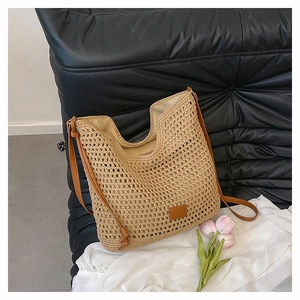 Detail of hand-woven straw shoulder bag with beige net texture and brown leather strap