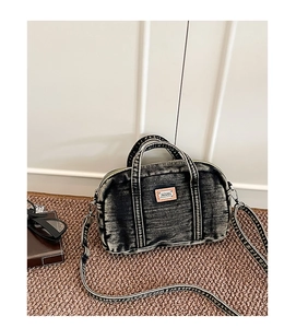 Détail du sac Boston en denim délavé gris avec bandoulière tissée et logo en cuir