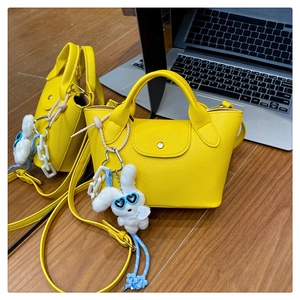 Detail of yellow lychee grain leather mini tote bag with cute plush rabbit charm