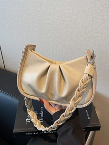 Chic beige cloud bag with pleated leather and woven handle in an elegant side view