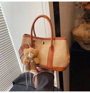 Détail du sac seau en paille tissée avec bordure en cuir marron et breloque ourson