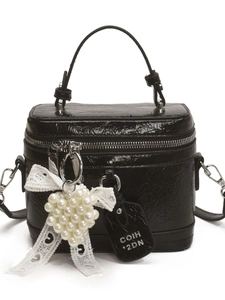 Glossy black handbag with pearl heart charm and lace bow on a clean white background