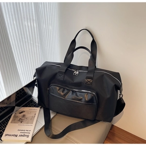 Black large travel duffel bag on grey stool with laptop, business lifestyle setting