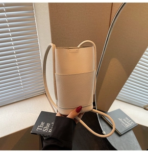 Close-up of cream white lychee pattern leather bucket bag with slim shoulder strap