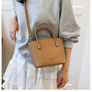 Caramel bucket handbag with pebbled texture and detachable shoulder strap on a model