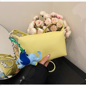Dettaglio borsa a bauletto gialla a grana di litchi con charm elefante blu e catena