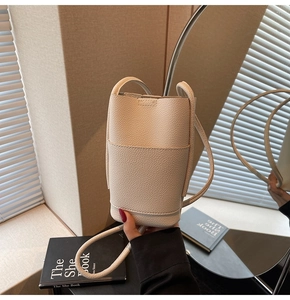 Close-up of beige lychee leather phone bag with minimalist stitching and front pocket detail