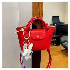 Detail of red pebbled leather mini tote with rabbit charm and gold snap button closure