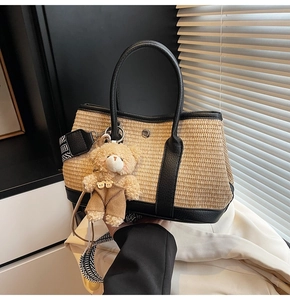 Détail du sac seau en paille tressée avec bordure en cuir noir et breloque ourson