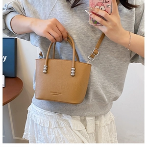 Brown leather bucket bag with silver beads shown in a mirror selfie style look