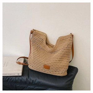 Close-up of beige woven shoulder bag with brown leather strap and brand label detail