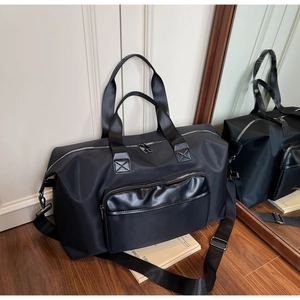 Close-up of black nylon travel bag with leather zipper pocket and adjustable strap