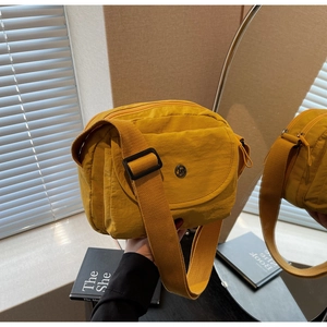 Detail einer hellgelben Nylon-Umhängetasche mit mehreren Reißverschlussfächern