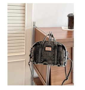 Détail du sac Boston en denim lavé avec logo en cuir et fermetures éclair métalliques