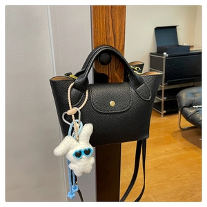Detail of black litchi grain tote bag with gold snap button and cute plush rabbit charm