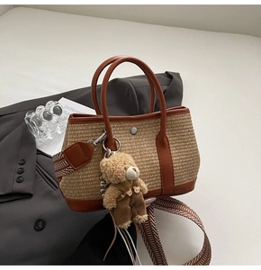 Détail du sac seau en paille avec garniture en cuir, bandoulière et breloque ours