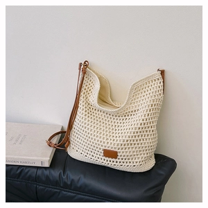 Detailed close-up of woven net texture and brown leather strap on cream crochet tote