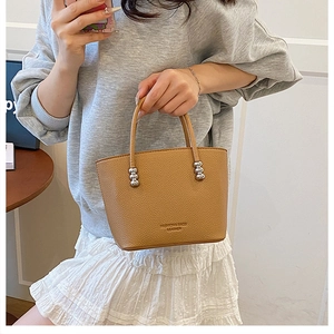 Detail of caramel lychee textured leather bucket bag with silver sphere handle accents