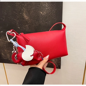 Dettaglio della borsa a bauletto in pelle rossa martellata con ciondolo a forma di elefante