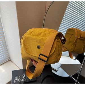 Detailansicht einer leuchtend gelben Nylon-Umhängetasche mit Vordertasche und Metalllogo