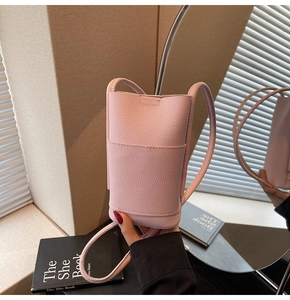 Detail of light pink pebble leather phone bag with slim shoulder strap and front pocket