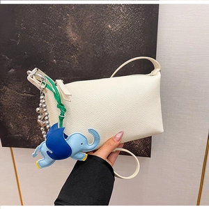 Dettaglio della borsa a tracolla bianca motivo litchi con ciondolo a forma di elefante