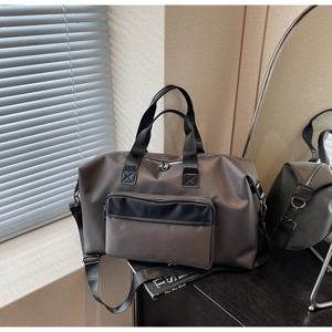 Close-up of durable dark grey travel duffel bag with black straps on a modern furniture piece
