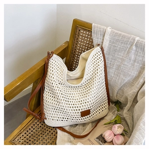 Detail of white crochet shoulder bag showing hollow knit texture and brown leather strap