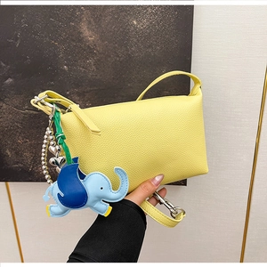 Dettaglio borsa a bauletto gialla in pelle PU con ciondolo a elefante e catena con cuori